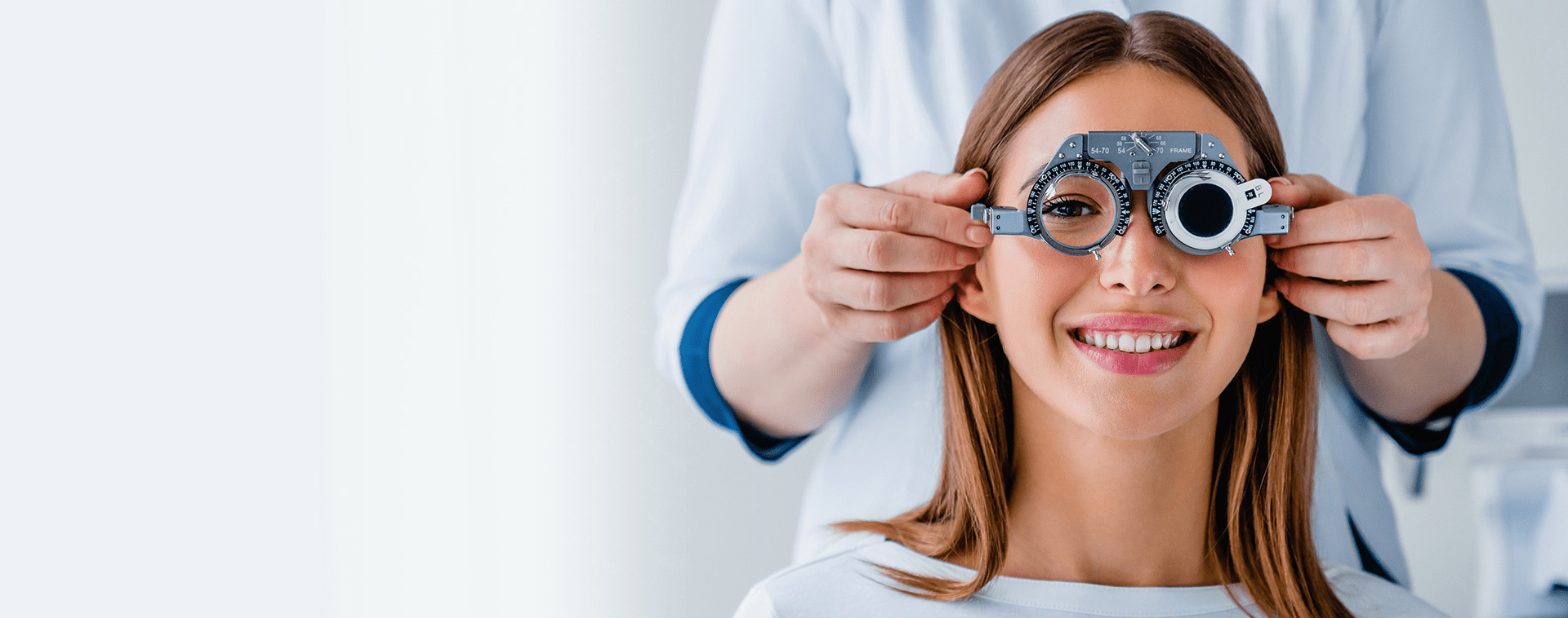 Arzt setzt eine Untersuchungsbrille einer jungen Dame mit langem Haar